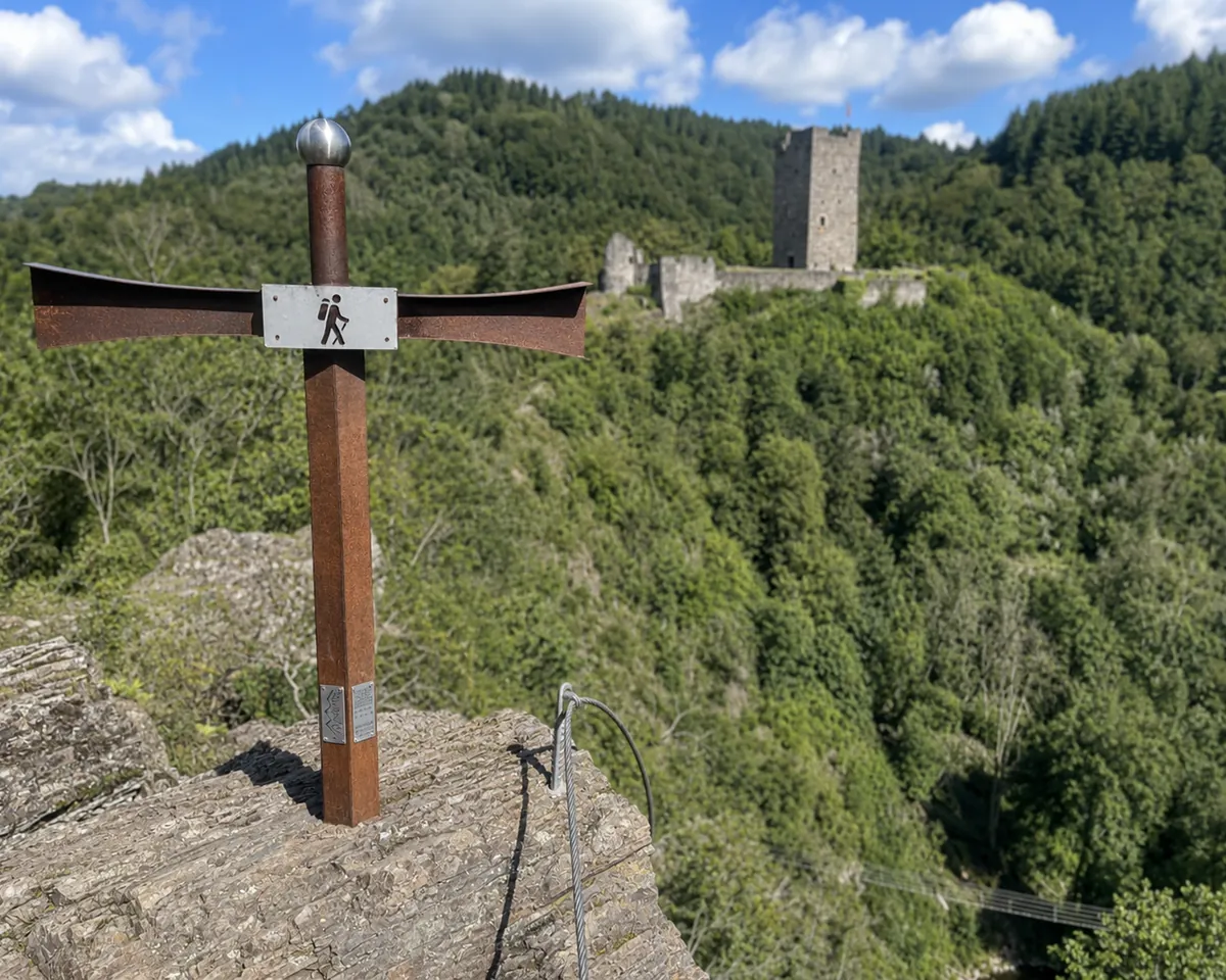 Wegkreuz am Burgenklettersteig mit Blick auf den Burgturm über dem Liesertal